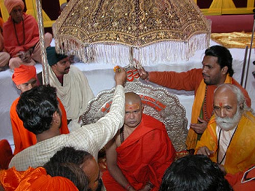 Priests are adorning Swamiji with tilak and flowers